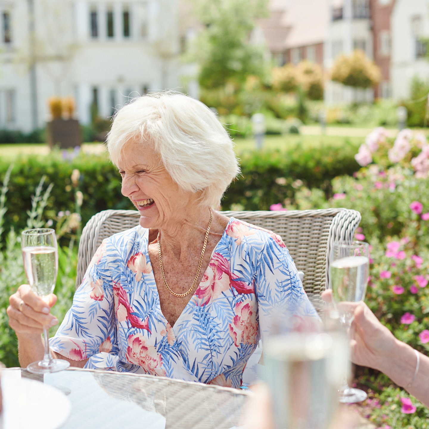 A woman laughing, holding a prosecco glass