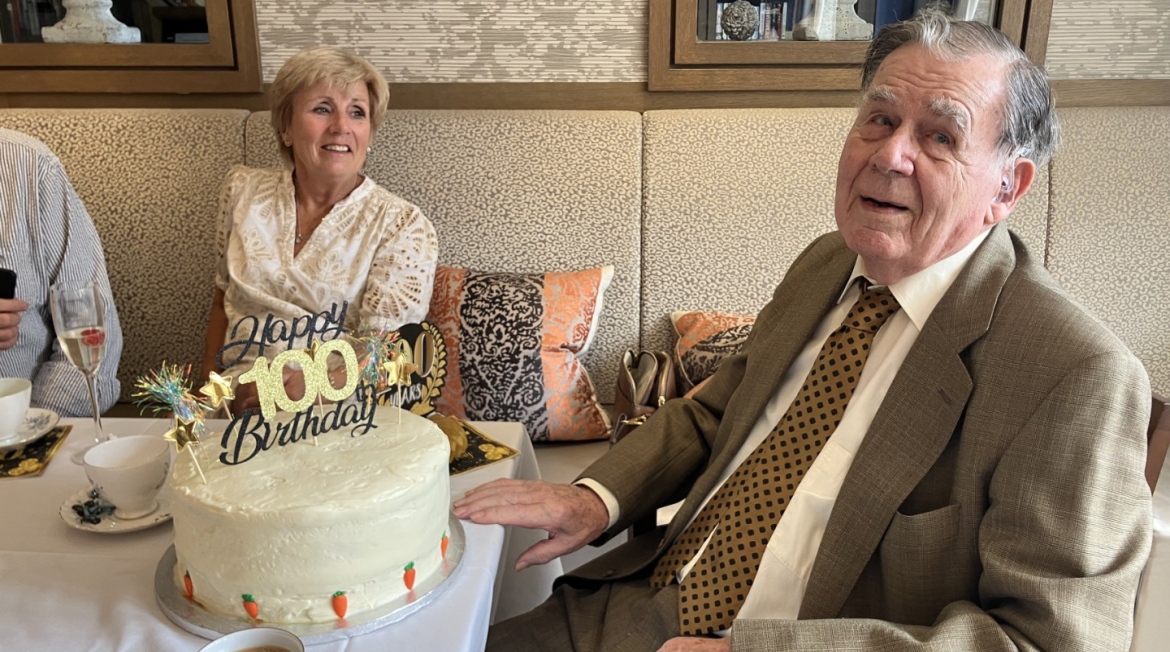 Two people sitting around a birthday cake