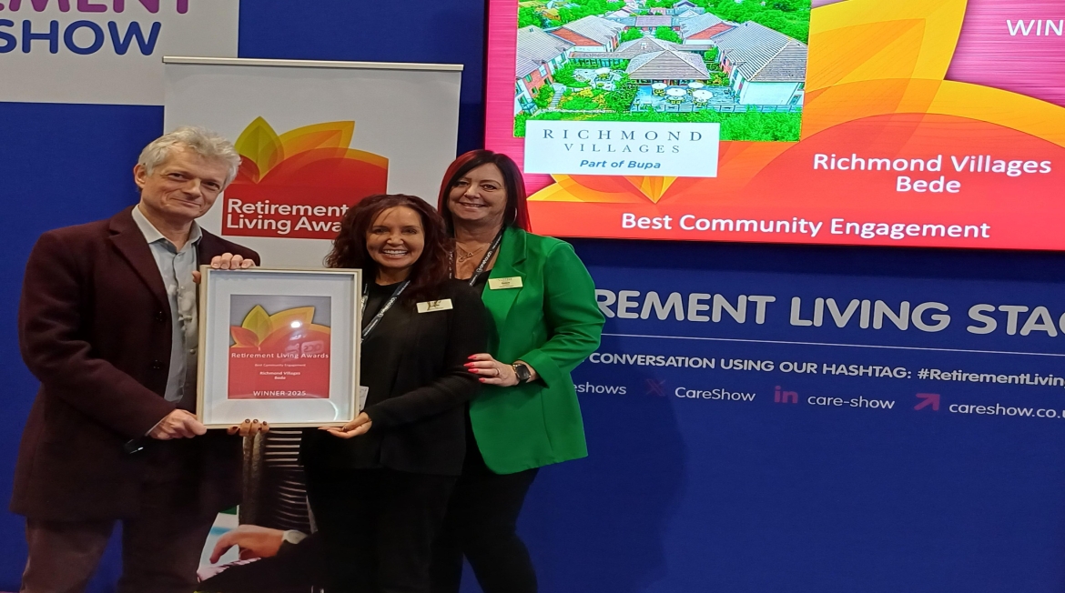 Three people holding a framed award.