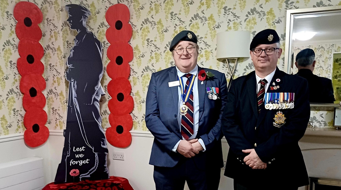 Two people with military medals standing next to a statue of a soldier.
