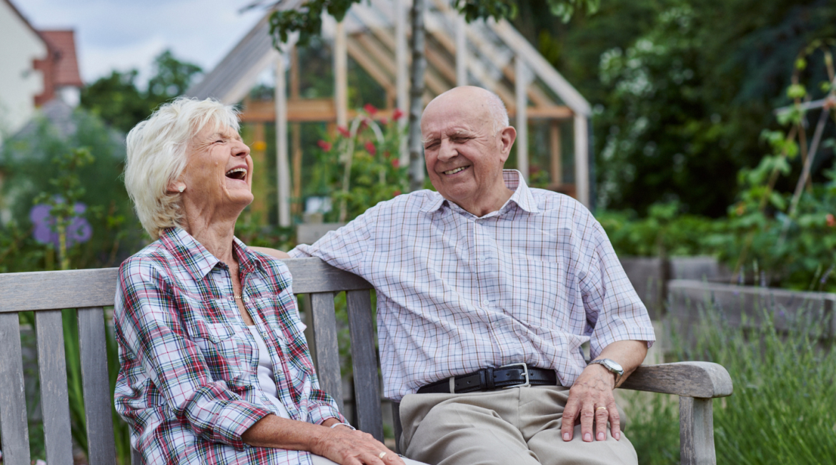 Two people set on a bench laughing