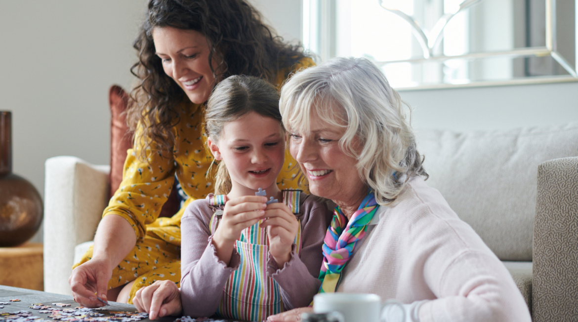 Three people sitting down playing with a jigsaw