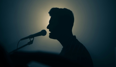 Silhouette of someone singing into a mic 