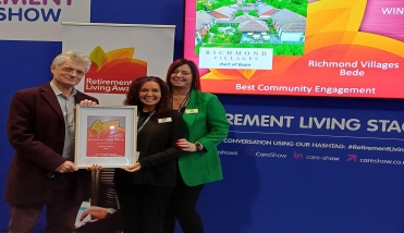 Three people holding a framed award.