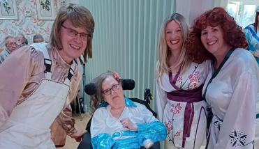 Three people dressed in ABBA costumes