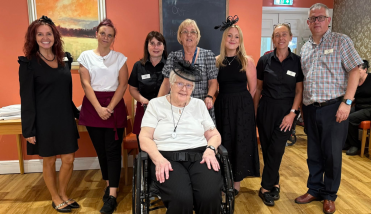 Seven people standing behind a lady in wheelchair