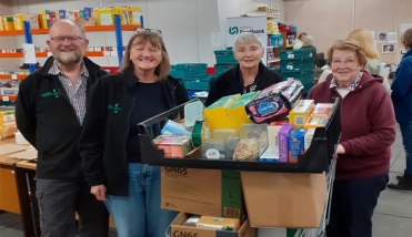 Four people standing by a trolley filled with food