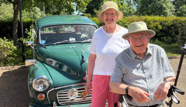 Two people standing in front of a classic car