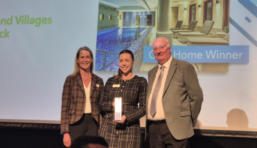 Three people standing, one holding an award