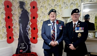 Two people with military medals standing next to a statue of a soldier.
