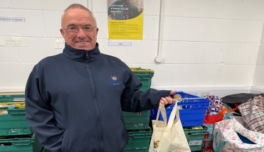 A man standing in a room with boxes holding a bag