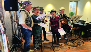 People singing into microphones wearing Christmas hats