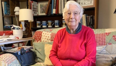 LADY IN RED JUMPER SMILING SITTING ON SOFA